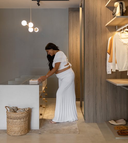Mulher organizando peças em um closet planejado com iluminação acolhedora